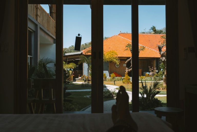 A view through a doorway of a tropical courtyard with orange tiled roofs