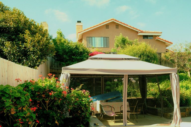 A backyard gazebo with a house and lush greenery