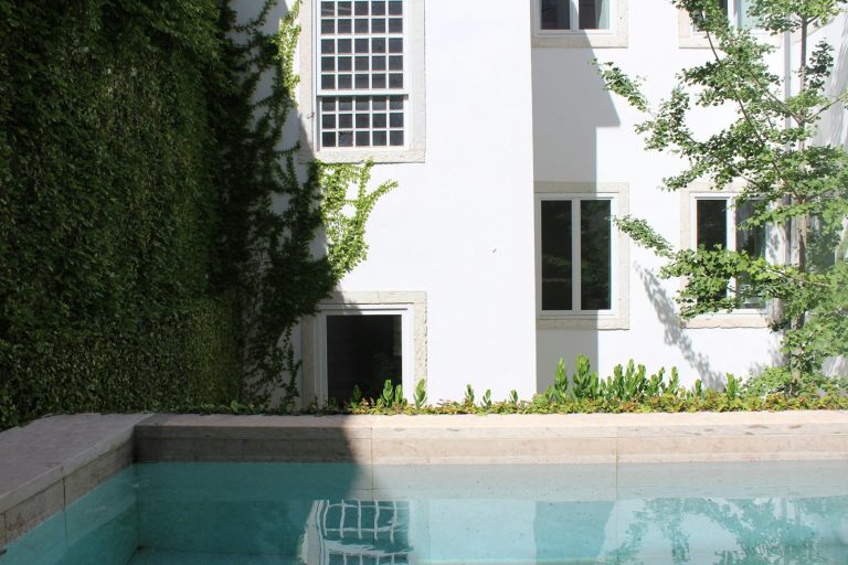 White building with ivy and swimming pool