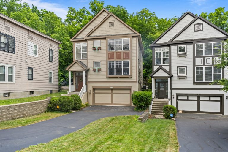 Three residential houses with driveways and green trees